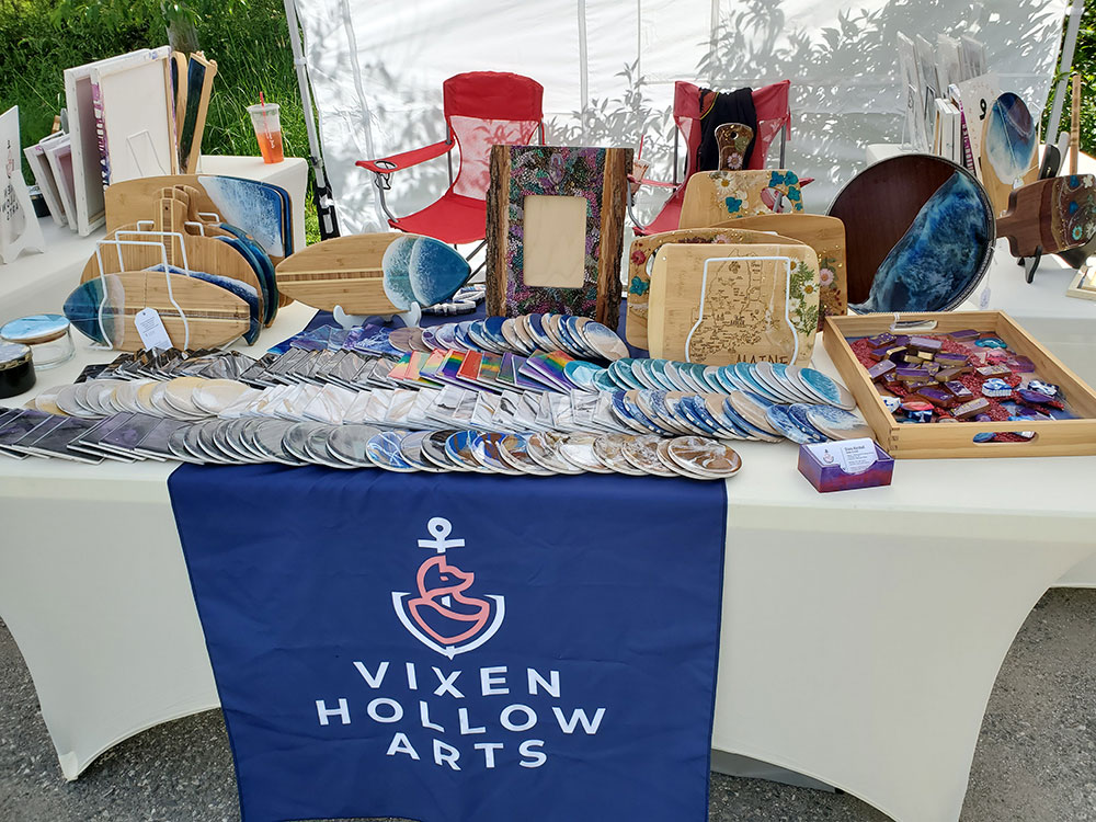 A table of wares with the Vixen Hollow Arts sign
