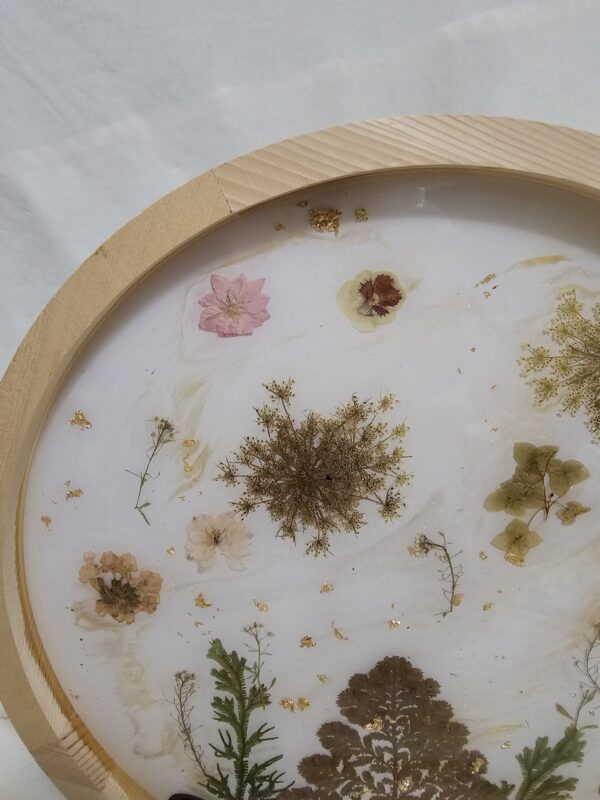 Round Wall art made of Pressed flowers and resin with rocks at the base. Neutral tones