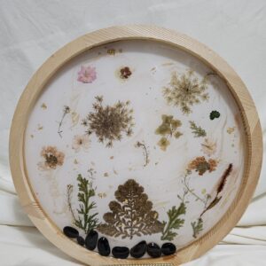 Round Wall art made of Pressed flowers and resin with rocks at the base. Neutral tones